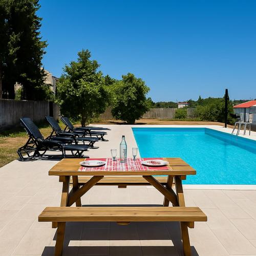 a wooden picnic table next to a swimming pool at Spacious House with Private Pool Kitchen in Teixoso