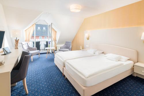 a hotel room with two beds and a desk and chairs at Hotel Inselfriede in Spiekeroog