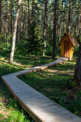a wooden path through a forest with a smallshed at Hosby Päkapikumaja Vormsi saarel in Hosby
