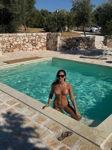 a woman in a bikini sitting in a swimming pool at Trulli di Titti - Luxury Country House in Castellana Grotte