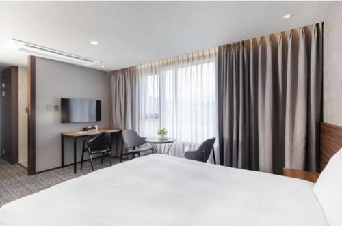 a hotel room with a large bed and a desk at With Stay Jeju Hotel in Jeju