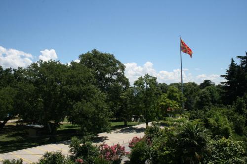 a flag pole in a park with trees and flowers at Villa Zora in Star Dojran