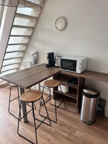 - une cuisine avec une table, des tabourets et un four micro-ondes dans l'établissement Duplex au cœur Annecy, à Annecy