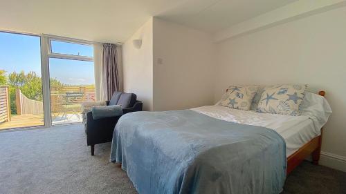 ニューキーにあるSea view Studio by Fistral Beachのベッドと椅子と窓のある寝室