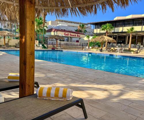 a pool with a bench with a pillow next to it at Aqaba Gulf Hotel By FHM in Aqaba