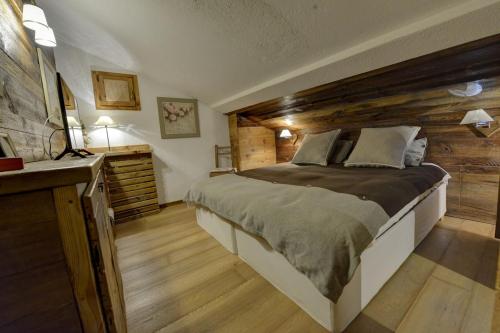 ein Schlafzimmer mit einem großen Bett und einer Holzwand in der Unterkunft Charme Alpine in Morgex