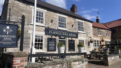 an old stone building with tables outside of it at The Forresters Arms Kilburn in Kilburn