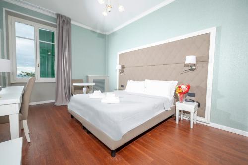 a bedroom with a large white bed and a desk at Grand Hotel & des Anglais Spa in Sanremo