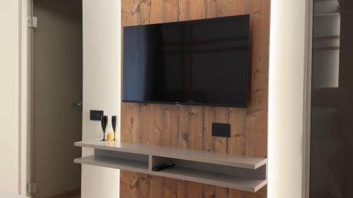 a television on a wooden wall with a shelf at A&F LUXURY Rooms Pinzolo in Pinzolo