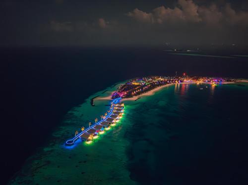 an island with lights in the water at night at Oaga Art Resort Maldives - Greatest All Inclusive Plan with Free Speedboat Round-trip in North Male Atoll