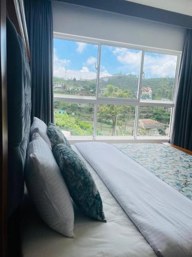 a bed with pillows sitting in front of a window at Ambula Resort in Nuwara Eliya