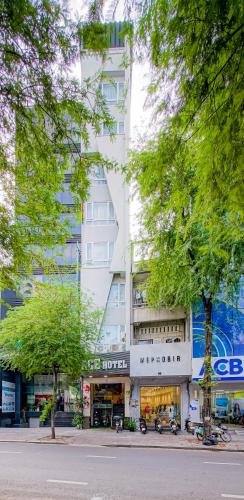 a white building with trees in front of it at Ace Hotel Ben Thanh in Ho Chi Minh City