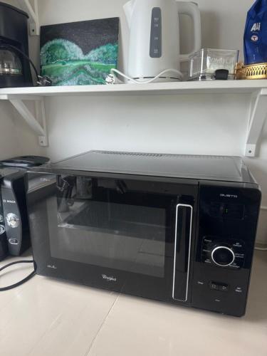 a black microwave sitting on a kitchen counter at Koselig leilighet på Østensjø med stor uteplass in Oslo