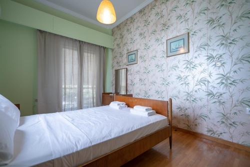 a bedroom with a bed with white sheets and floral wallpaper at Retro 2-Bdrm House Near Metro in Heraklion by ΜΡS in Athens