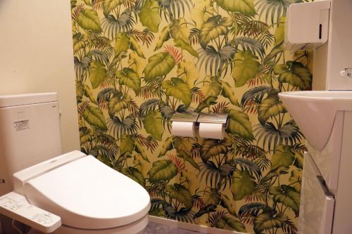 a bathroom with a toilet with a yellow and green wallpaper at Ocho Guest House in Sapporo