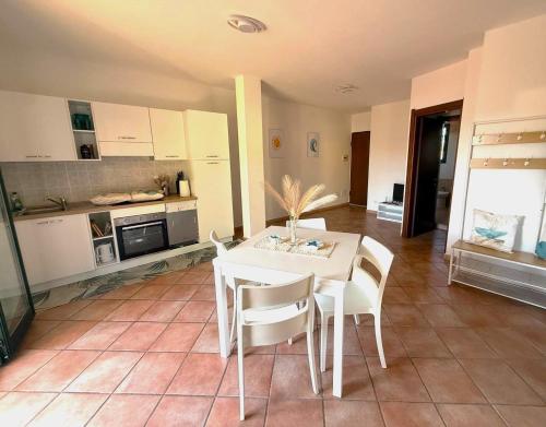 a kitchen with a white table and white chairs at Affittimoderni Valledoria - Costa Dora in Valledoria