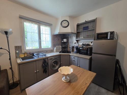 a kitchen with a refrigerator and a table with a clock at Studio en bas de villa in Puget-sur Argens
