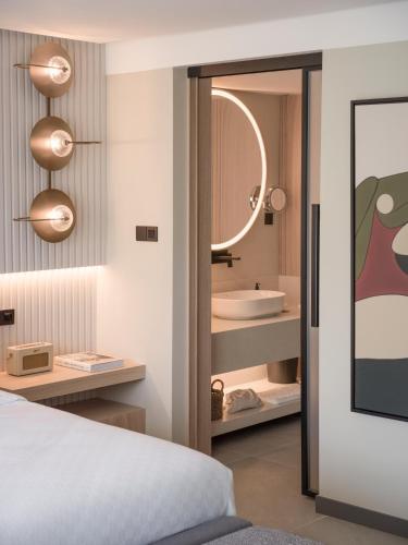 a bedroom with a bed and a bathroom with a sink at kolektif suites in Kérynia