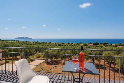 a table with a bottle and a glass of wine on a balcony at Seaview and Sunsets - Beachside Retreats in Ayía Kiriakí