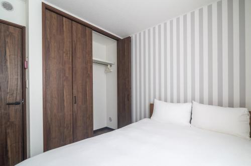 Un dormitorio con una cama blanca y una puerta de madera. en 新屋 札幌市中心 近圓山公園 挑高設計客廳 4房 2廁所 1浴室 1淋浴 最大10人 可停車, en Sapporo