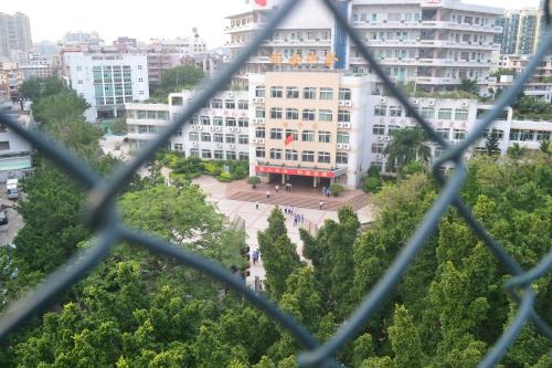 a view of a building from a chain link fence at Notting Hill Hostel in Bao'an
