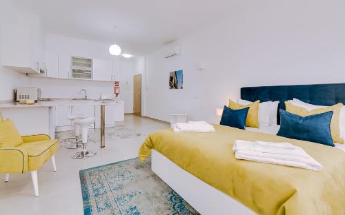 a bedroom with a large bed and a kitchen at Apartamentos Sol & Ria in Olhão