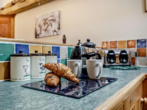 a counter top with a tray with a croissant and cups at 2 bed property in Tattersett KT125 in Tattersett