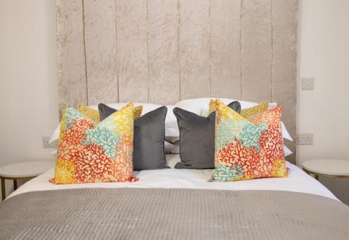 a bed with colorful pillows on top of it at Luxury City Retreat Perfect for Business & Families & Free Gym By The Pocklington - The New Walk Suite in Leicester