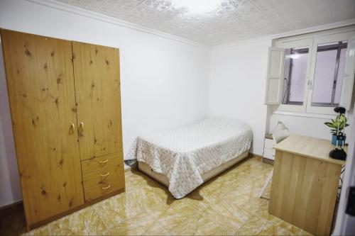 ein Schlafzimmer mit einem Bett und einem Holzschrank in der Unterkunft Habitación individual acogedora in Alicante