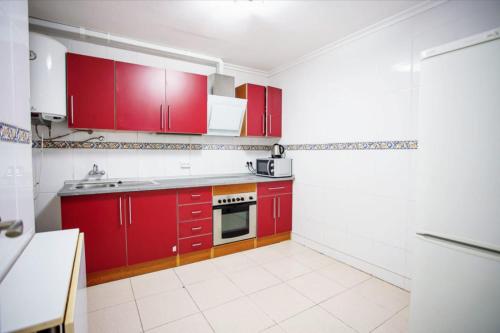 eine rote Küche mit roten Schränken und einem Herd in der Unterkunft Habitación individual acogedora in Alicante