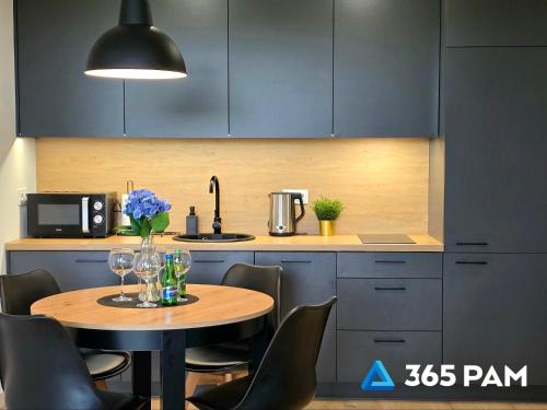 cocina con mesa de madera con sillas y fregadero en Westin House Rodzinny z 2 sypialniami - BASEN, JACUZZI, SAUNA, SALA FITNESS, PLAC ZABAW, PARKING W CENIE - 365PAM, en Kołobrzeg