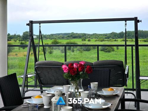 Una mesa con un jarrón de flores en un balcón. en Westin House Rodzinny z 2 sypialniami - BASEN, JACUZZI, SAUNA, SALA FITNESS, PLAC ZABAW, PARKING W CENIE - 365PAM, en Kołobrzeg