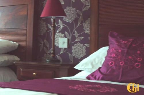 a bedroom with a bed with a purple pillow and a lamp at Grand Central Hotel in Ó Méith