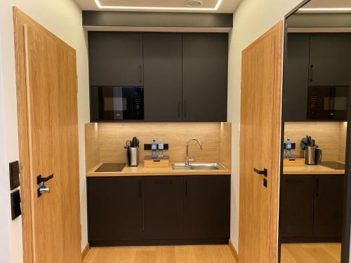 a kitchen with black cabinets and a sink at Zielona Ostoja - Pokoje i Apartamenty in Nowa Sarzyna