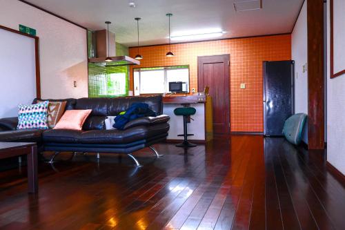 a living room with a leather couch and a kitchen at villa live okinawa in Uruma