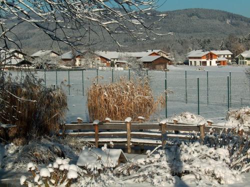 a wooden bench covered in snow next to a fence at Schlossberghof Marzoll in Bad Reichenhall