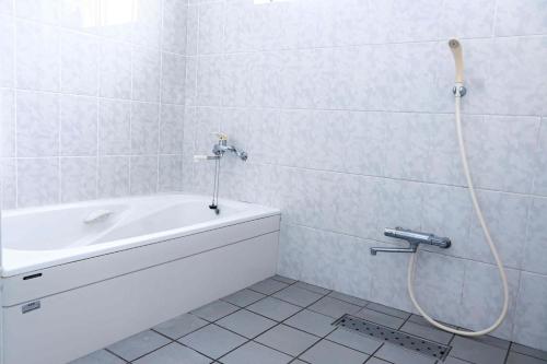 a bathroom with a bath tub with a hose on the wall at villa live okinawa in Uruma