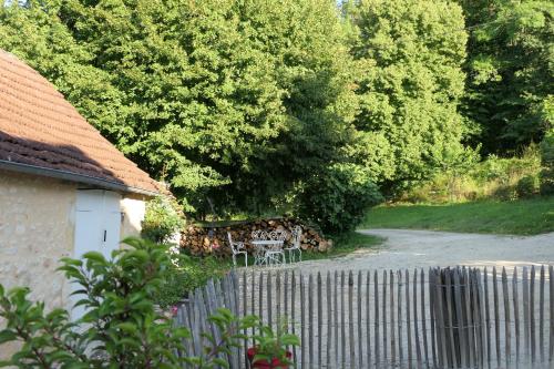 a garden with a table and a fence and trees at Maison des hôtes in Campagne