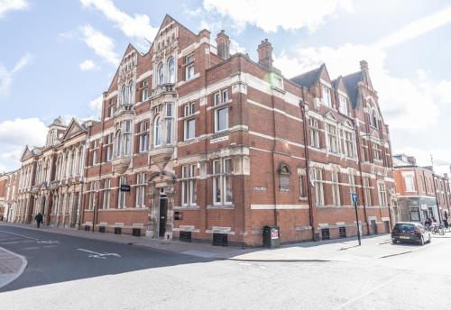 a large red brick building on a city street at Luxury City Retreat Perfect for Business & Families & Free Gym By The Pocklington - The New Walk Suite in Leicester
