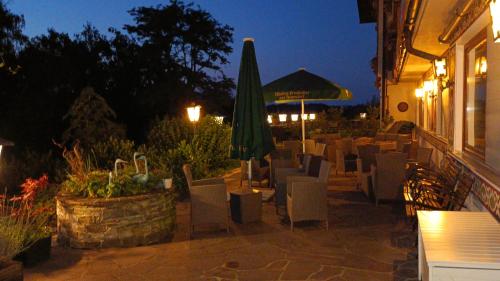 a restaurant patio with chairs and an umbrella and a table at Schlossberghof Marzoll in Bad Reichenhall