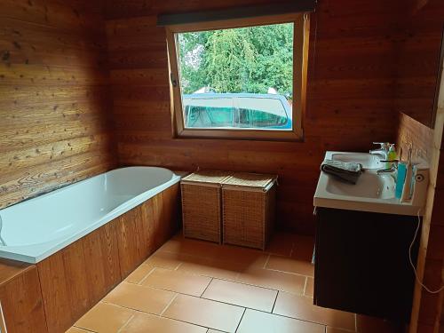 a bathroom with a tub and a sink and a window at Gîte de la Croix Regnault in Raids