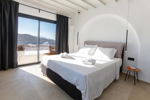 a bedroom with a large bed and a large window at Amazē Mykonos in Mikonos