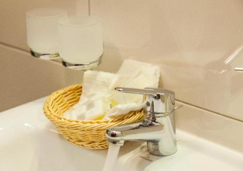 a bathroom sink with a faucet and a basket of toiletries at Villa MB in Augustów