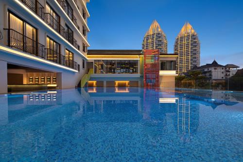 a hotel swimming pool with buildings in the background at voco Xishuangbanna Gaozhuang by IHG in Jinghong