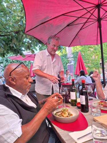 two men sitting at a table under an umbrella at La Retraite in Assignan