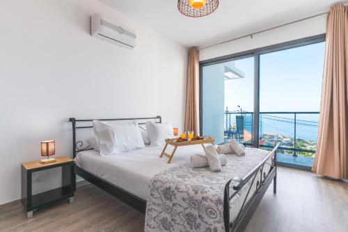 a bedroom with a bed and a large window at Casa Teixeira by Atlantic Holiday in Estreito da Calheta