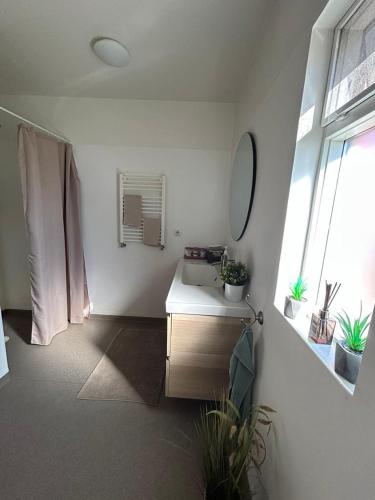 a bathroom with a sink and a mirror and a window at Syðra-Skörðugil Guesthouse in Varmahlid