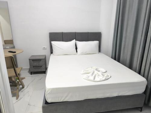 a bedroom with a bed with white sheets and a whitevisorvisor at Delvina Central Rooms by Mira in Delvinë