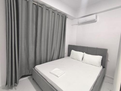 a small bedroom with a bed with a gray curtain at Delvina Central Rooms by Mira in Delvinë