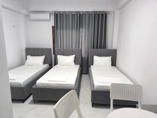 a room with two beds and a table and chairs at Delvina Central Rooms by Mira in Delvinë